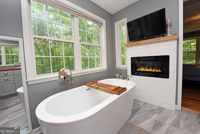 bathroom featuring a glass covered fireplace and a freestanding tub