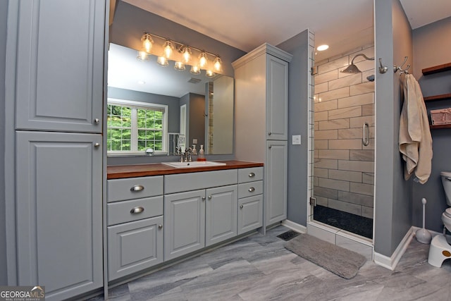 bathroom with vanity, toilet, baseboards, and a stall shower