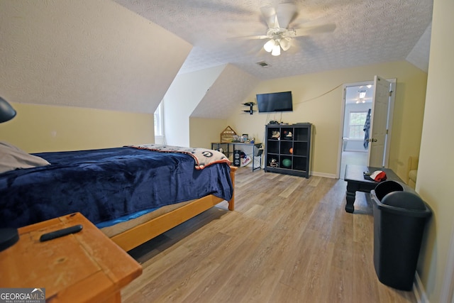 bedroom with wood finished floors, baseboards, ceiling fan, a textured ceiling, and vaulted ceiling