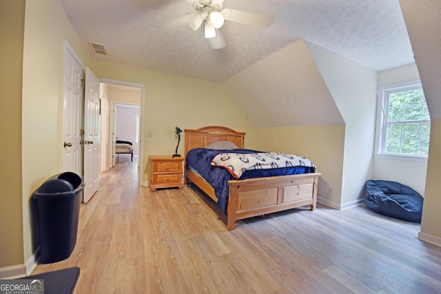 bedroom with visible vents, baseboards, light wood-type flooring, a textured ceiling, and a ceiling fan