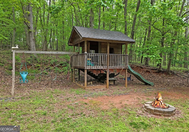 view of playground featuring a fire pit and a forest view