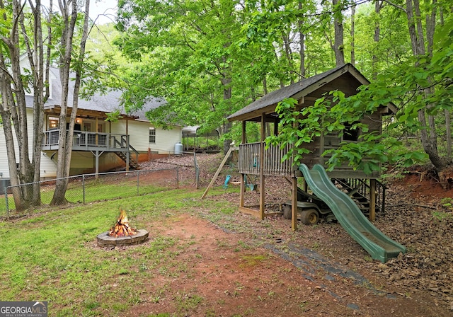 view of yard featuring fence, a fire pit, and a playground