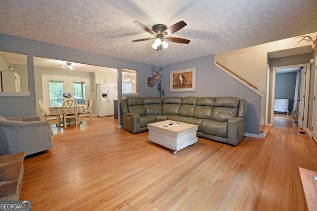 living room featuring light wood-style floors, a textured ceiling, and ceiling fan