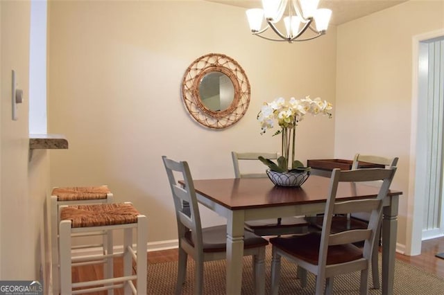 dining space featuring baseboards, a chandelier, and wood finished floors