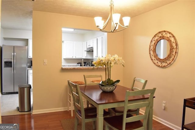 dining space featuring an inviting chandelier, baseboards, and wood finished floors