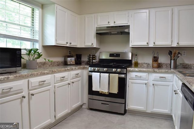 kitchen with light tile patterned floors, white cabinets, stainless steel appliances, and under cabinet range hood