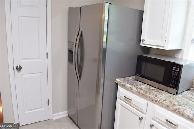 kitchen with light stone counters, stainless steel fridge with ice dispenser, white cabinetry, baseboards, and light tile patterned floors