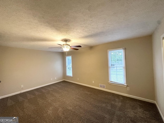 unfurnished room featuring visible vents, a textured ceiling, baseboards, and dark colored carpet
