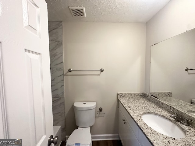 bathroom featuring a textured ceiling, visible vents, vanity, baseboards, and toilet