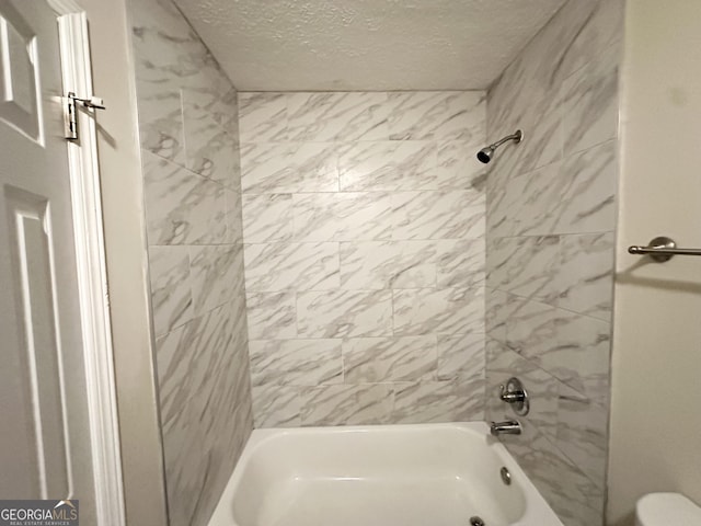 bathroom featuring a textured ceiling, bathtub / shower combination, and toilet