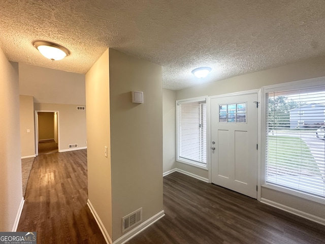 entrance foyer featuring visible vents, baseboards, a textured ceiling, and wood finished floors
