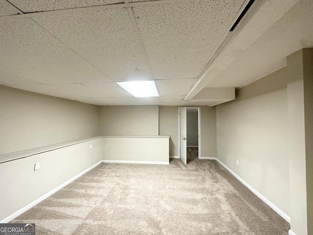 finished below grade area with baseboards, a drop ceiling, and carpet