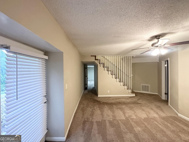 interior space with baseboards, a textured ceiling, visible vents, and ceiling fan
