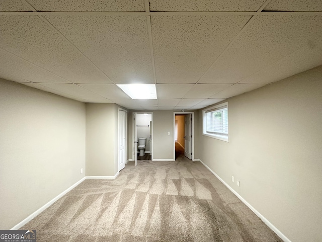 below grade area featuring carpet floors, baseboards, and a drop ceiling