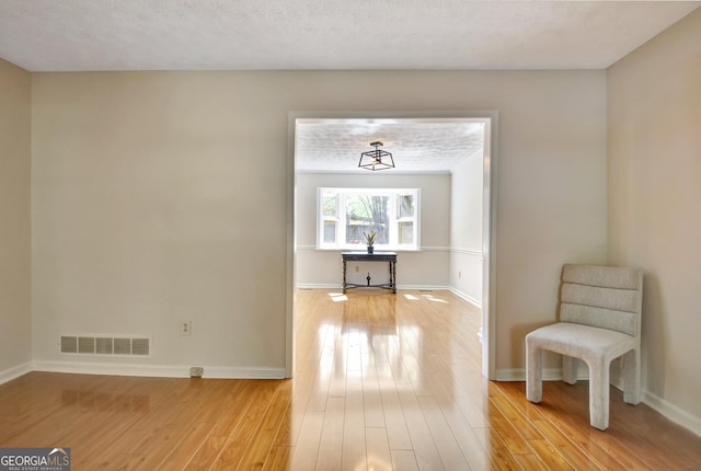 interior space featuring light wood-style floors, baseboards, and visible vents