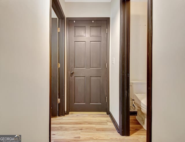 corridor featuring baseboards and light wood finished floors