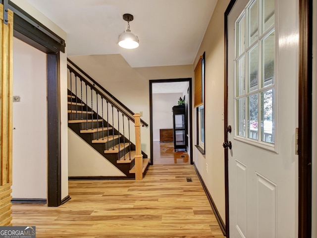 entrance foyer featuring baseboards, stairway, and light wood-style floors