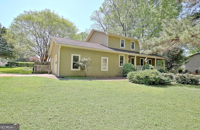 rear view of property featuring roof with shingles, covered porch, and a yard