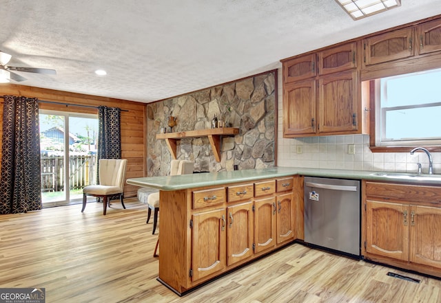 kitchen featuring a sink, stainless steel dishwasher, a peninsula, and a textured ceiling