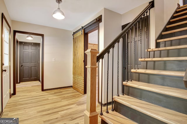 staircase with a barn door and wood finished floors