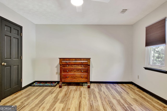 spare room featuring a ceiling fan, baseboards, and light wood-style flooring