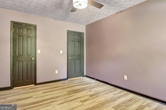 empty room with a ceiling fan, a textured ceiling, baseboards, and light wood-type flooring