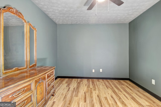 empty room with light wood-style floors, a ceiling fan, a textured ceiling, and baseboards