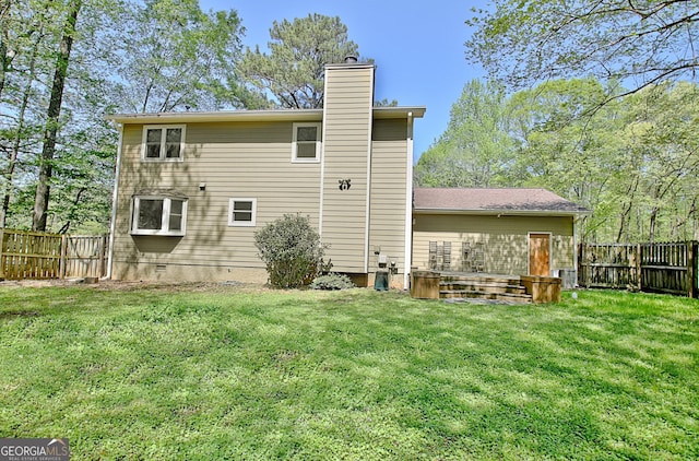 rear view of house with a lawn, a fenced backyard, and a chimney