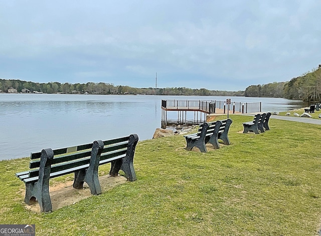 view of dock with a lawn and a water view
