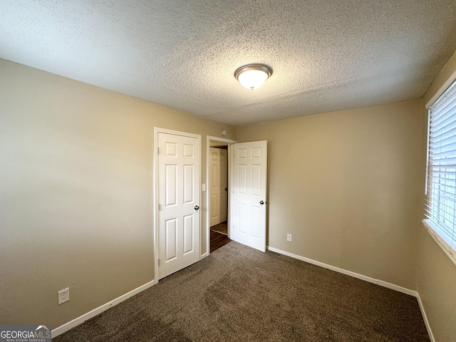 unfurnished bedroom featuring a textured ceiling, baseboards, multiple windows, and carpet