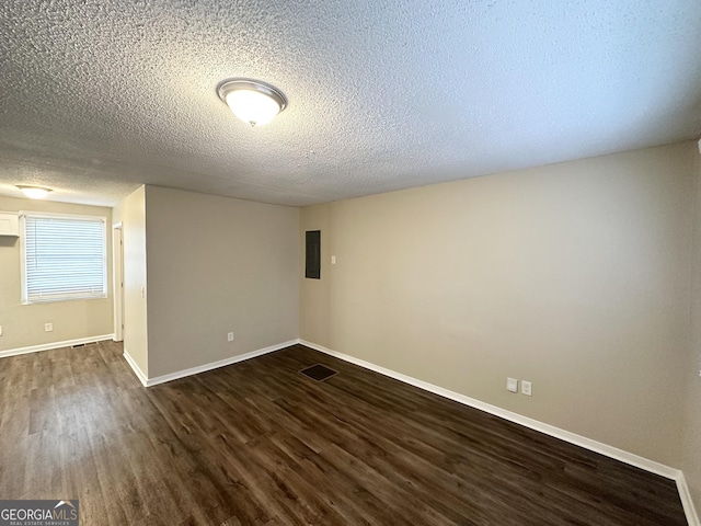spare room featuring visible vents, baseboards, dark wood-style floors, a textured ceiling, and electric panel