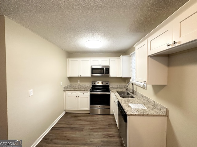 kitchen with a sink, appliances with stainless steel finishes, dark wood-style flooring, and white cabinetry
