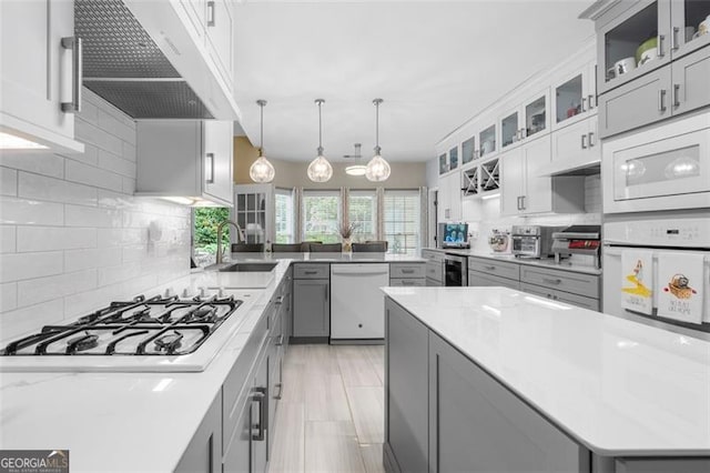 kitchen with wine cooler, white appliances, under cabinet range hood, a sink, and gray cabinetry