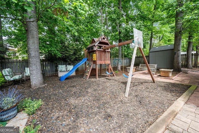 view of jungle gym featuring an outdoor structure, a fenced backyard, and a storage shed