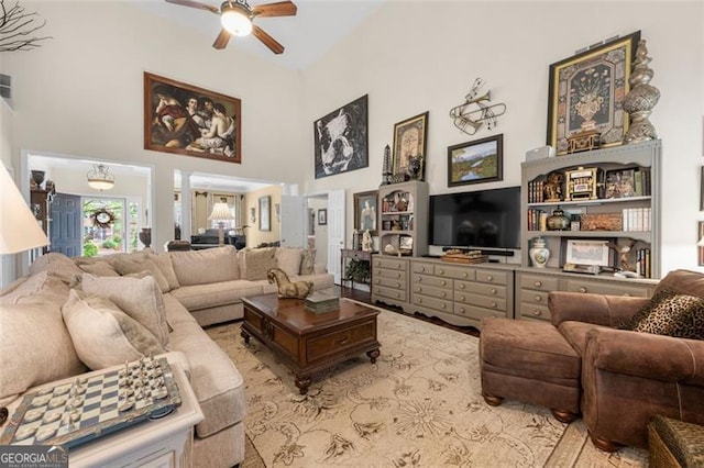 living area featuring visible vents, a ceiling fan, and a high ceiling