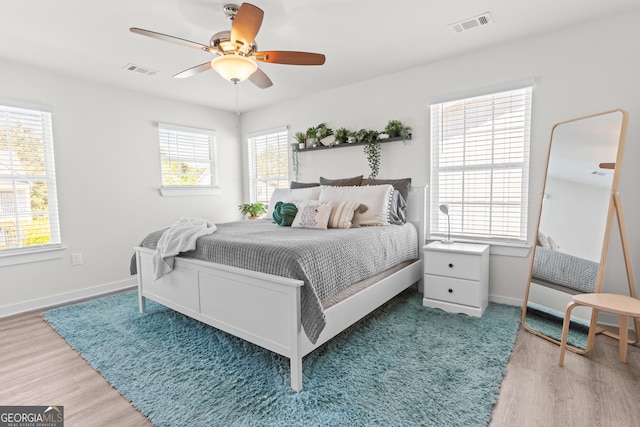 bedroom with visible vents, a ceiling fan, baseboards, and wood finished floors