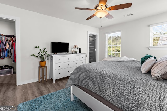 bedroom with visible vents, wood finished floors, baseboards, a closet, and a spacious closet