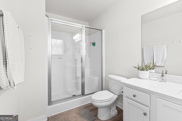 bathroom featuring vanity, wood finished floors, toilet, and a shower stall