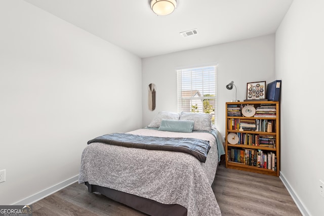 bedroom with baseboards, wood finished floors, and visible vents