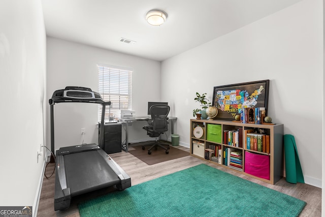 home office with baseboards, wood finished floors, and visible vents