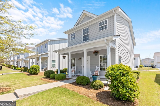 view of front of home featuring covered porch, board and batten siding, and a front yard