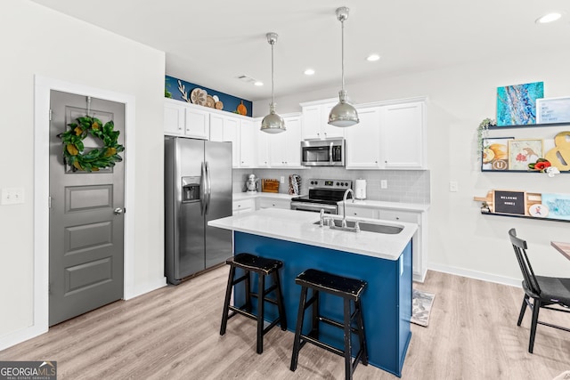 kitchen featuring tasteful backsplash, a sink, light countertops, light wood finished floors, and stainless steel appliances