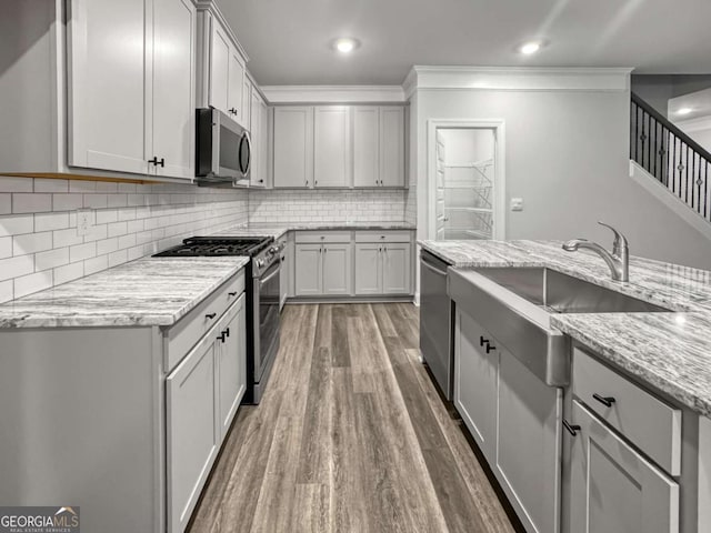 5291 Tuscany Dr, Douglasville, GA 30135 - kitchen featuring wood finished floors, light stone countertops, a sink, appliances with stainless steel finishes, and backsplash