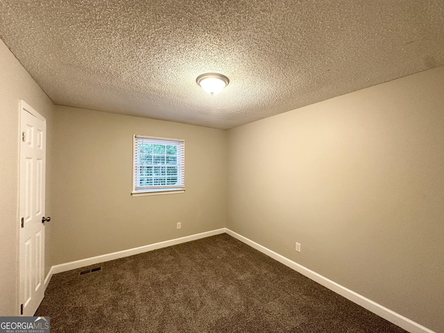 empty room featuring visible vents, a textured ceiling, baseboards, and dark carpet