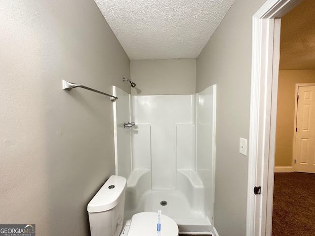 bathroom featuring toilet, a textured ceiling, walk in shower, and baseboards