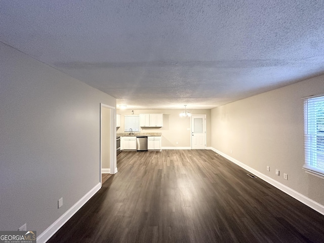 unfurnished living room with baseboards, a textured ceiling, and dark wood finished floors
