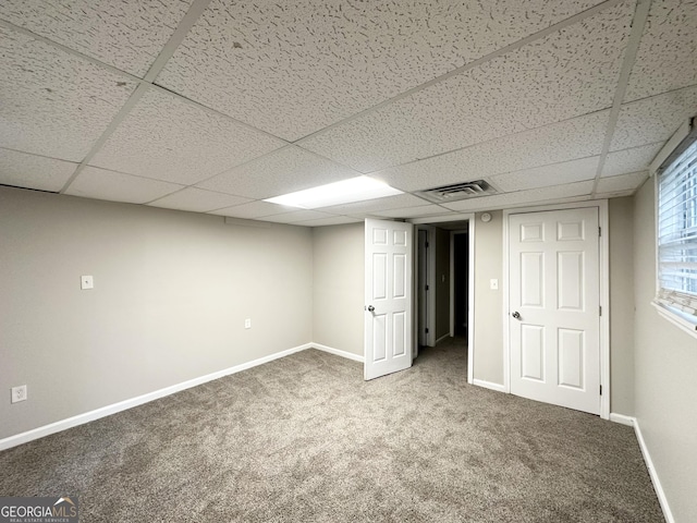 basement featuring baseboards, visible vents, a drop ceiling, and carpet