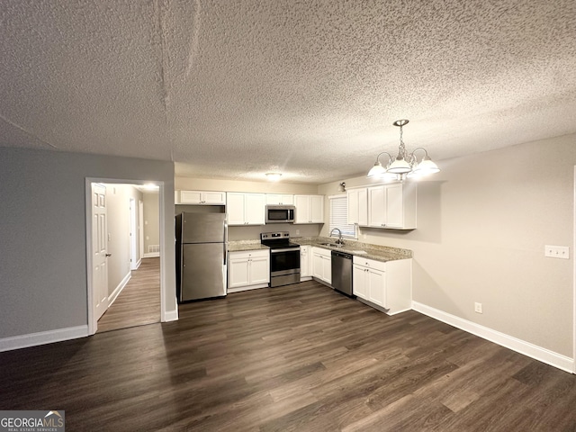 kitchen with a textured ceiling, stainless steel appliances, baseboards, white cabinetry, and dark wood-type flooring