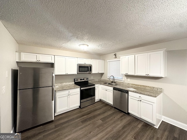 kitchen with white cabinets, appliances with stainless steel finishes, a sink, and dark wood finished floors