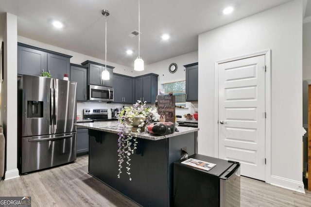 kitchen featuring pendant lighting, light stone countertops, a center island with sink, light wood finished floors, and stainless steel appliances